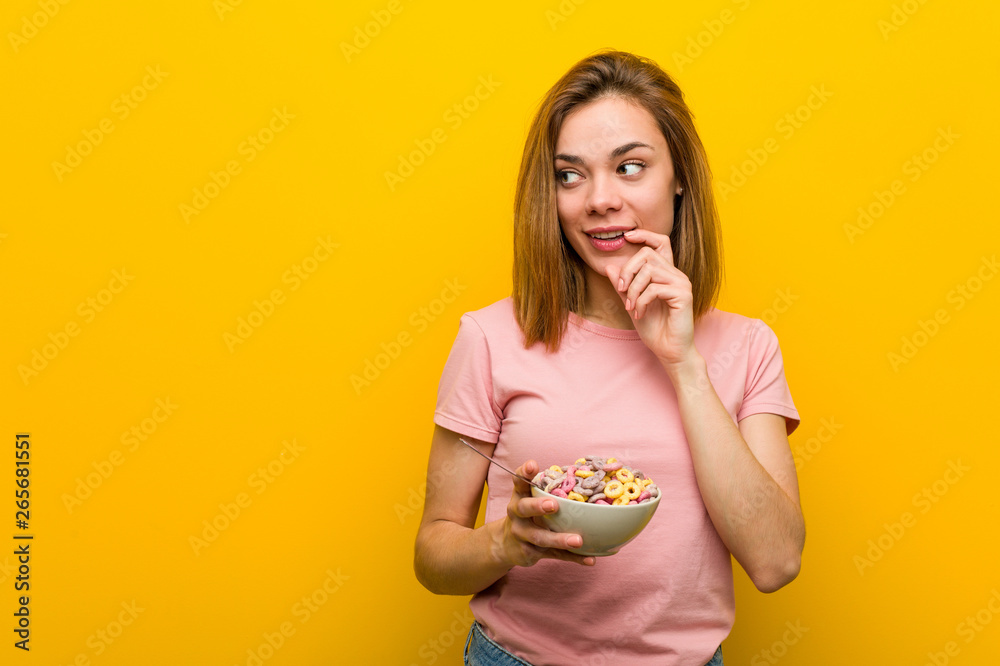 Young woman holding a cereals bowl relaxed thinking about something looking at a copy space. Young woman holding a cereals bowl relaxed thinking about something looking at a copy space.