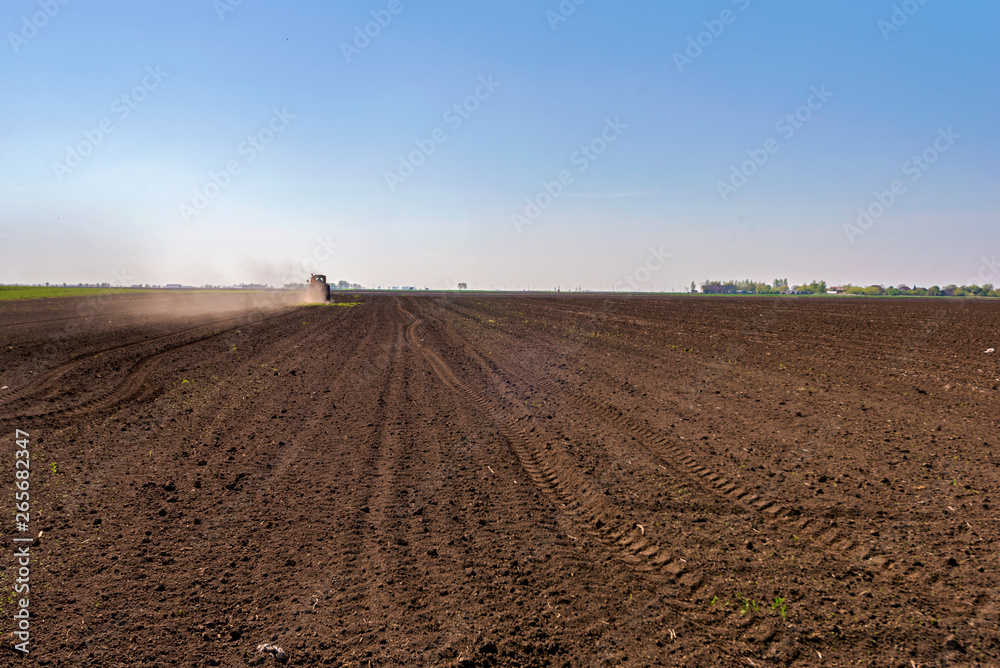 Tractor spraying a soil with fertilizer. Fertilization of soil. Early spring time. Tractor spraying a soil with fertilizer. Fertilization of soil. Early spring time.