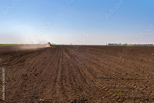 Tractor spraying a soil with fertilizer. Fertilization of soil. Early spring time. © lordn