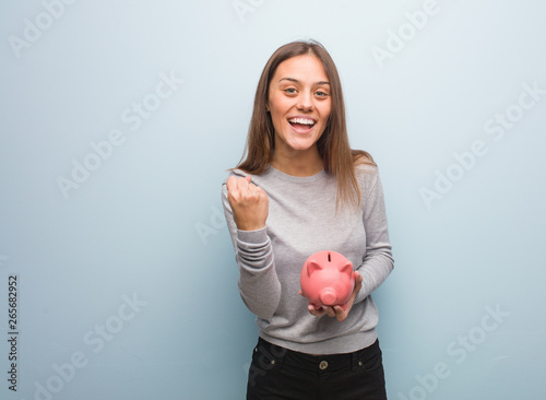 Young pretty caucasian woman surprised and shocked. She is holding a piggy bank.