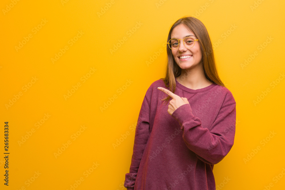 Young casual woman smiling and pointing to the side Young casual woman smiling and pointing to the side