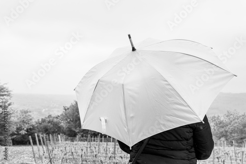 A woman with orange umbrella waits for rain