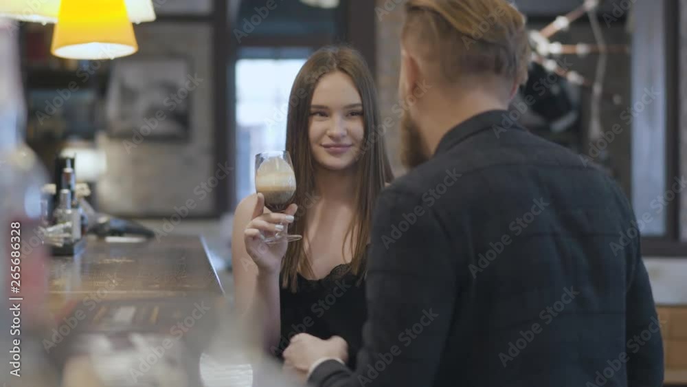 Cute young brunette woman and blond bearded man sitting at the bar counter close up. Concept of night lifestyle. Cute couple has a date. Cute young brunette woman and blond bearded man sitting at the bar counter close up. Concept of night lifestyle. Cute couple has a date.