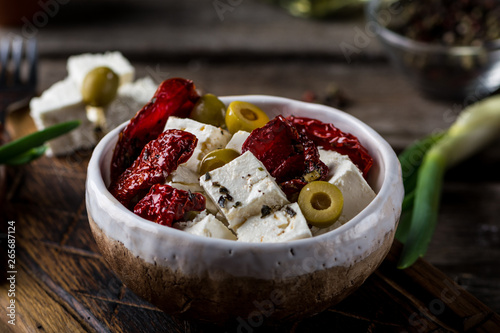 Greek cheese feta with herbs and olives, sundried tomatoes. Bulgarian cheese. Feta in oil. Olove oil. selective focus. appetizer photo