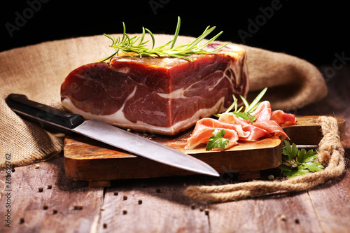 Italian prosciutto crudo or jamon with rosemary. Raw ham on wooden board