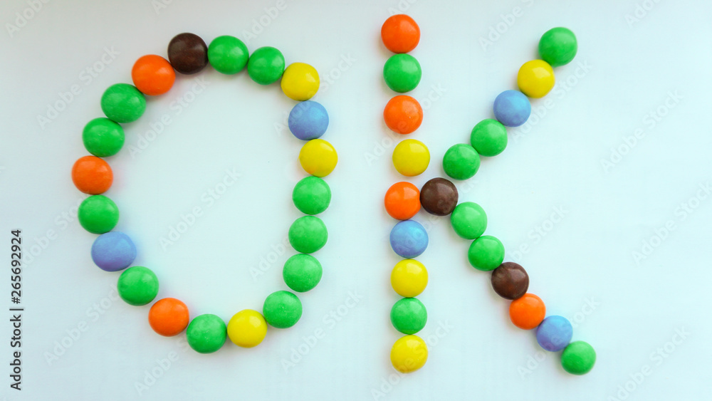 Obraz premium Phrase OK made of color candies on white background