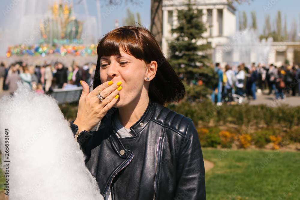 Close up portrait of a smiling excited girl holding cotton candy in the park close to fountain. Close up portrait of a smiling excited girl holding cotton candy in the park close to fountain.