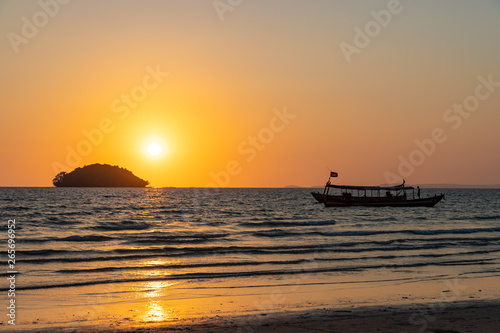 Beautiful orange sunset with the silhouette of a island and boat in Otres, Cambodia.