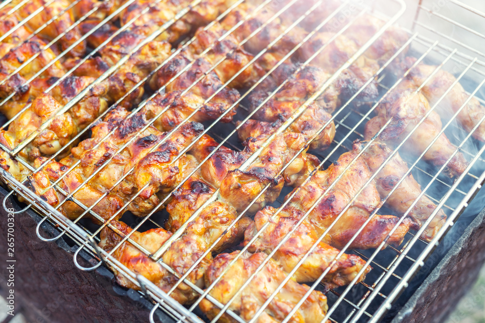 Close-up chicken wings cooking in metal barbecue grid on grill brazier. Outdoors weekend party on backyard. Tasty golden brown delicious bbq meal