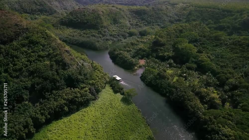 An aerial follow shot of a small riverboat cruising down a beautiful river on a tropical island paradise. An aerial follow shot of a small riverboat cruising down a beautiful river on a tropical island paradise.