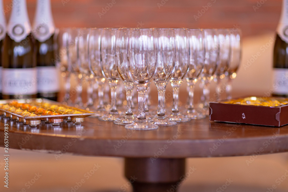 wine glasses arranged on the table in the shape of a triangle,candy in a box and a bottle of champagne