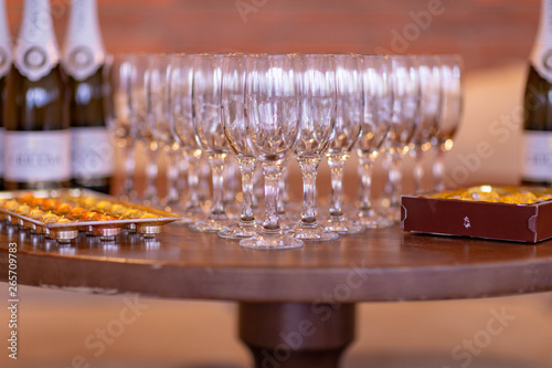 wine glasses arranged on the table in the shape of a triangle,candy in a box and a bottle of champagne
