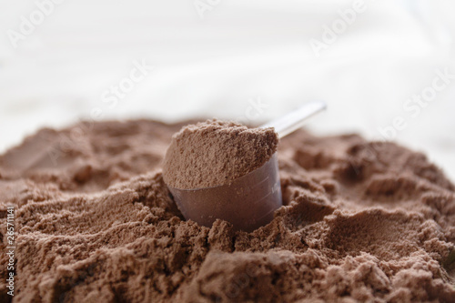 Wallpaper Mural Product photograph of spoon or measuring scoop of whey protein. Whey protein powder sports bodybuilding supplement. Plastic scoop on wooden background with chocolate powder flavour. Torontodigital.ca