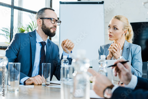 selective focus of bearded businessman talking near coworkers in conference room