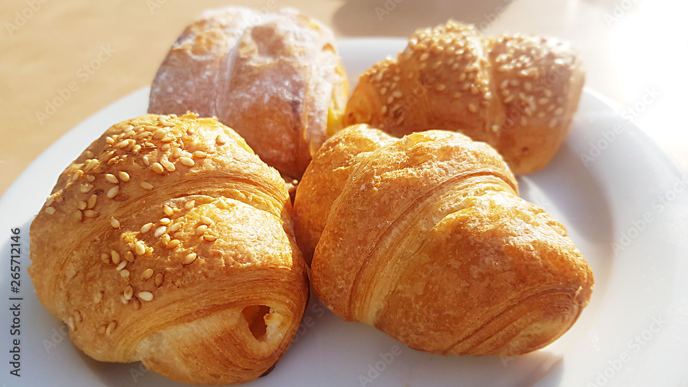 fresh croissants with natural sunlight on plate traditional french breakfast with coffee 
