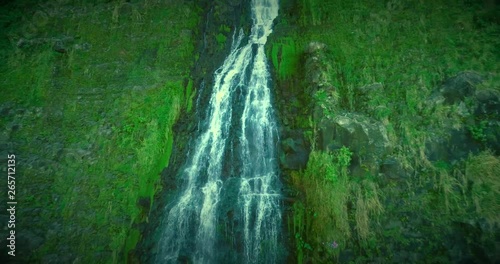 Slow motion aerial drone shot of a waterfall flowing into the ocean in Waipio Valley on the Big Island of Hawaii. Drone is flying up the waterfall. photo