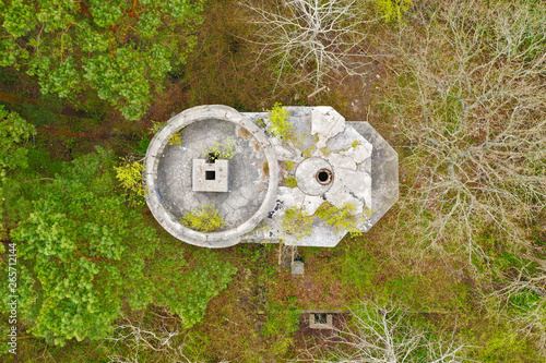 Aerial top down view on ruined and old tower bunker hidden in deep forest photo