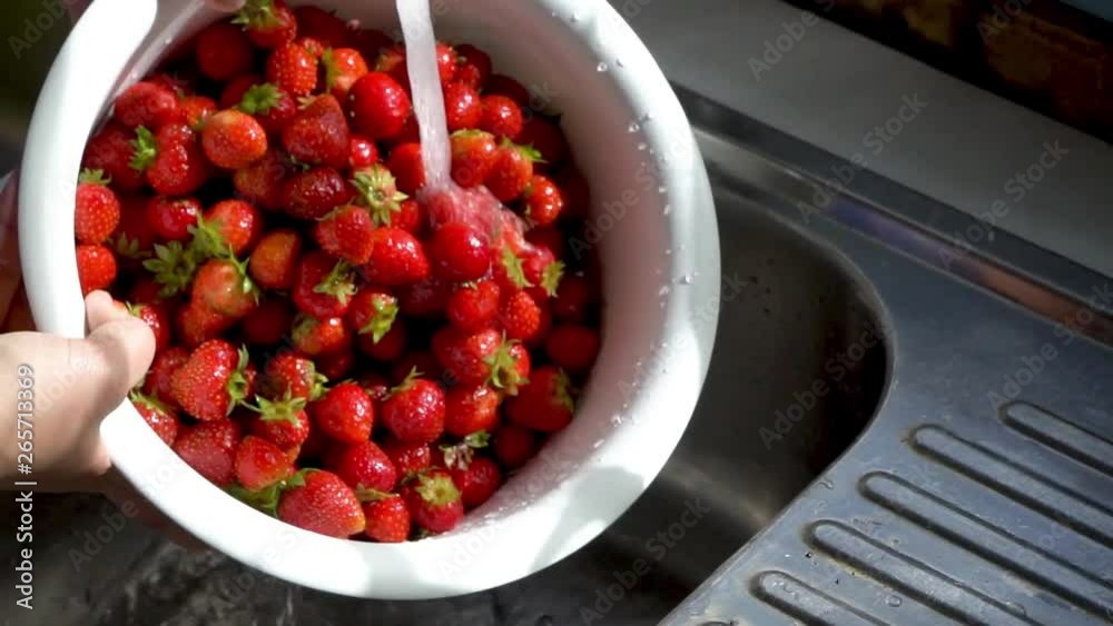 Slow motion close up washing a bowl of freshly picked strawberries under running water Slow motion close up washing a bowl of freshly picked strawberries under running water