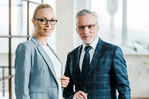 Foto cheerful businesswoman and businessman in eye glasses looking at camera