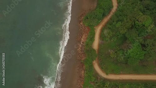 Aerial view of interesting dirt road between small ocean waves and central american jungle photo