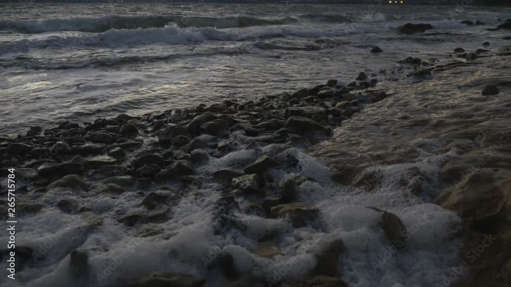 Slow motion of waves rolling in over rocks on foreshore causing ocean foam on windy dusk evening. Slow motion of waves rolling in over rocks on foreshore causing ocean foam on windy dusk evening.