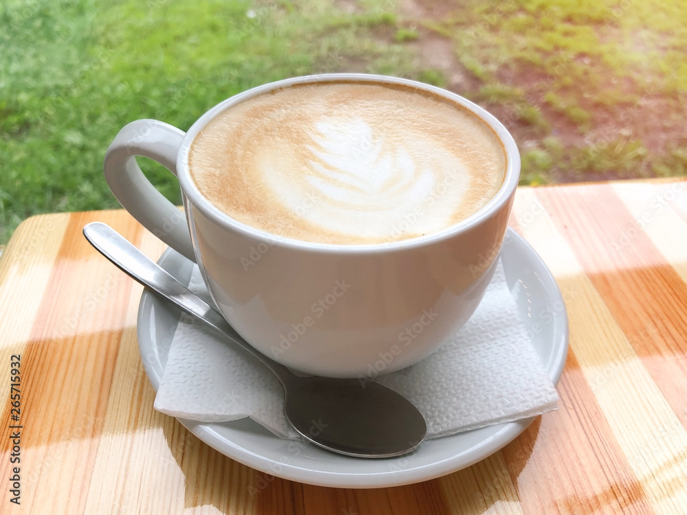A large white cup of cappuccino with milk standing on a wooden table. Coffee mood. The concept of a break, pause. Delicious aromatic hot drink for relaxation. Close-up, yellow toning, warm atmosphere. A large white cup of cappuccino with milk standing on a wooden table. Coffee mood. The concept of a break, pause. Delicious aromatic hot drink for relaxation. Close-up, yellow toning, warm atmosphere.