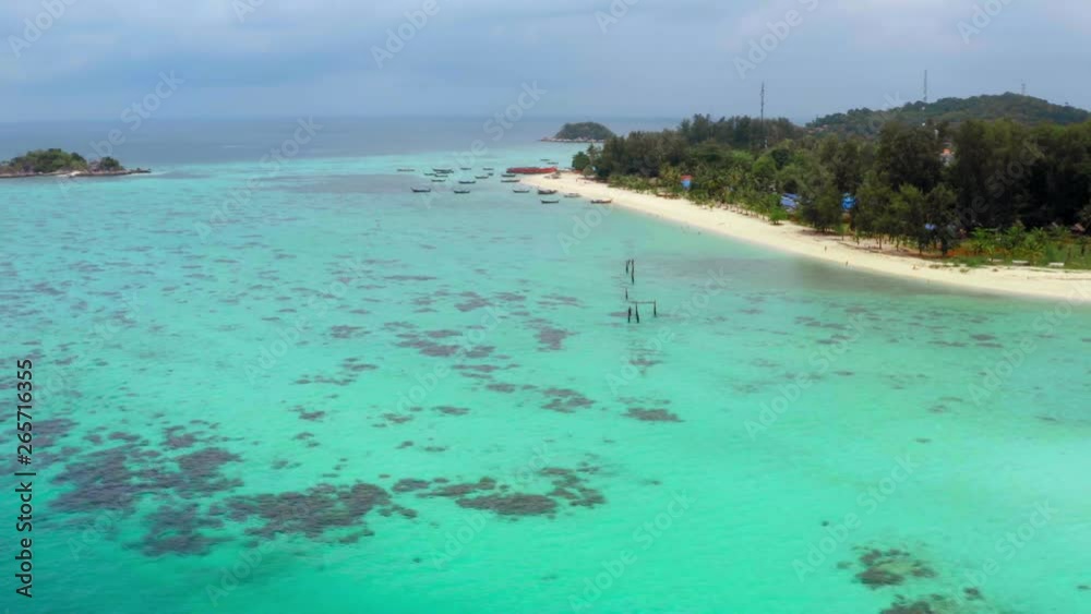 Low angle aerial rotation across crystal blue clear coral reef waters off Koh Lipe tropical jungle island resort. Gorgeous idyllic holiday destination. Low angle aerial rotation across crystal blue clear coral reef waters off Koh Lipe tropical jungle island resort. Gorgeous idyllic holiday destination.