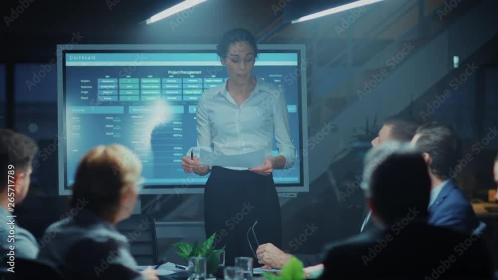 In the Corporate Meeting Room: Female Project Manager Points and Shows Animated Graphs and Statistics on a Digital Interactive Whiteboard, Does talk and Presentation for the Investors and Executives In the Corporate Meeting Room: Female Project Manager Points and Shows Animated Graphs and Statistics on a Digital Interactive Whiteboard, Does talk and Presentation for the Investors and Executives