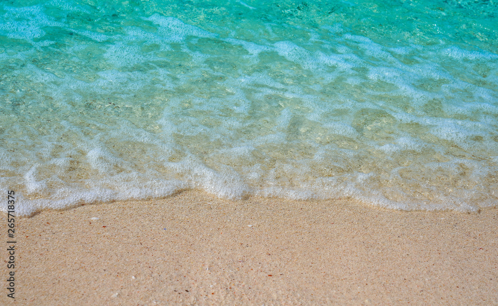 Soft wave of blue ocean on sandy beach Background  with white wave bubbles.