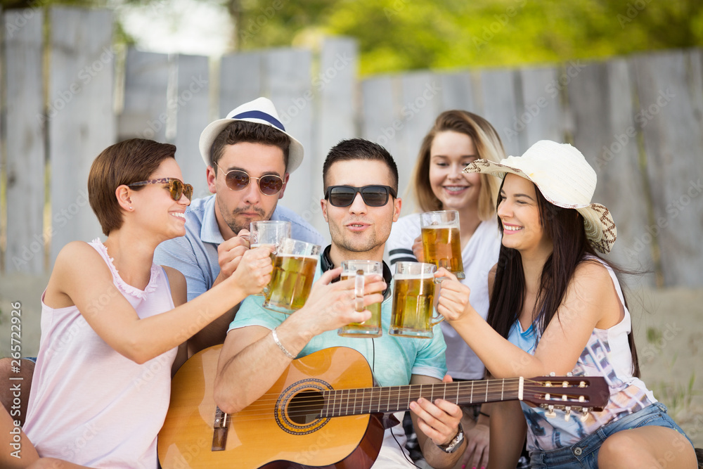 Young group of people with a beer and guitar outdoors Young group of people with a beer and guitar outdoors