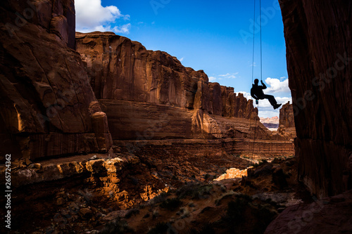 Entering a narrow canyon hanging in air, rappelling in Arches National Park, Utah. photo