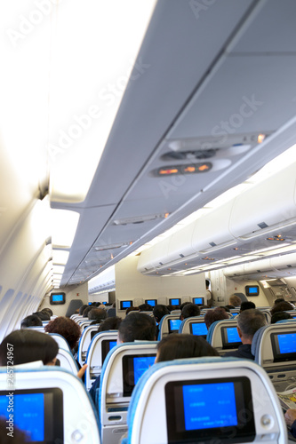 irplane cabin full of passengers during a flight viewed from the back with a view