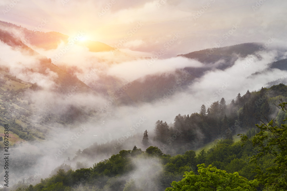 Summer mountain panorama. Small wooden house cottage and barn on green mountain valley on bright foggy sky, clouds and mountain