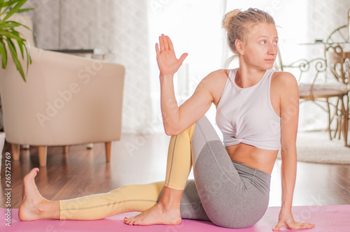 Beautiful woman is practicing yoga, doing Ardha Matsyendrasana pose at home photo