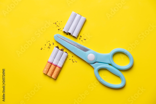 Bild auf Leinwand Blue scissors cut cigarette and tobacco on yellow background pastel tone
