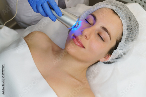 Hardware cosmetology. Ultrasound chromotherapy. Beautician carries out procedure for tightening skin of face. Spa. Non-surgical cosmetology. Skin elasticity