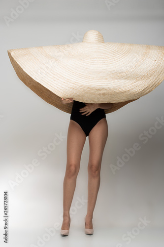 Asian Beautiful tan skin woman in Fashion black Swimwear stand on high heel shoes wear very big hat straw, studio lighting white gray backgrounds, copy space for text logo