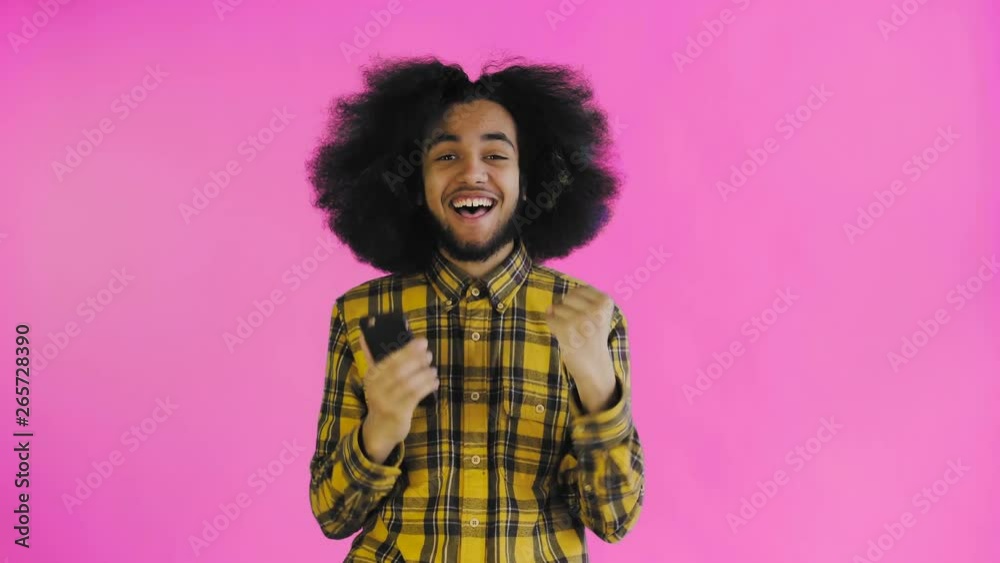 Young happy African businessman using phone and getting good news on purple background. Concept of emotions Young happy African businessman using phone and getting good news on purple background. Concept of emotions