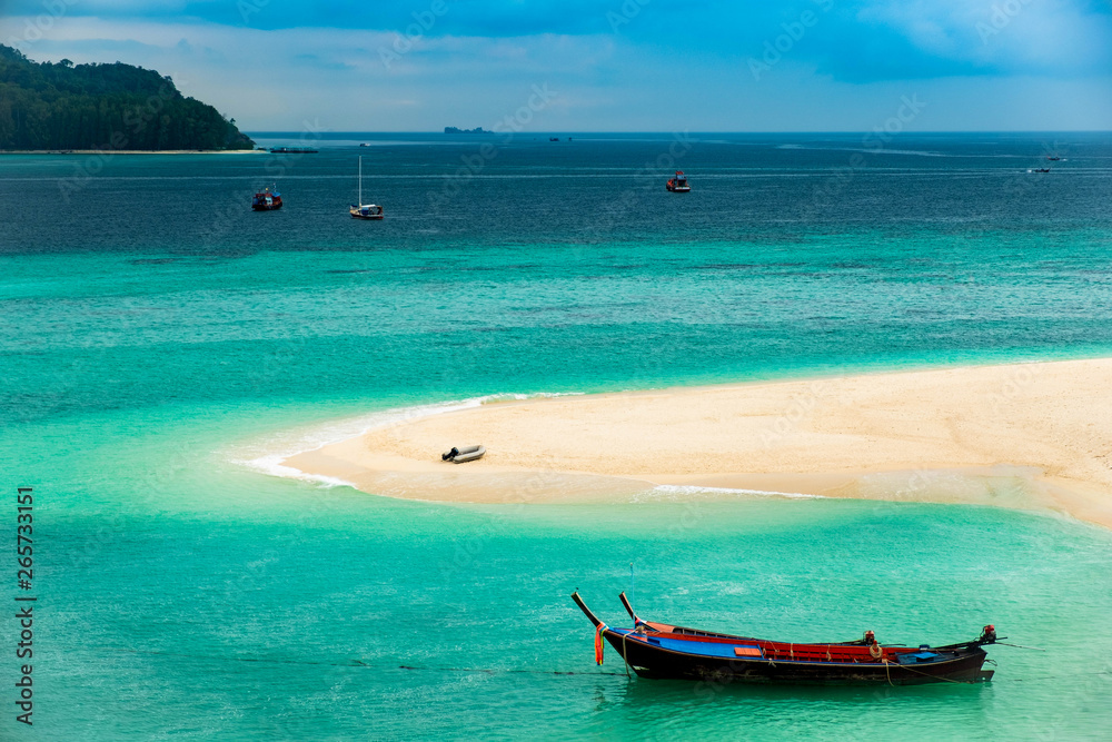 Beach that extends into the sea Looking out to see the island And blue sky There are many boats floating in the emerald green sea of the Andaman Sea. At Sunrise Beach, Koh Lipe, Satun, Thailand