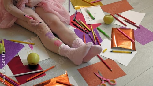 little girl draws on her feet with felt-tip pens, children's creativity, development