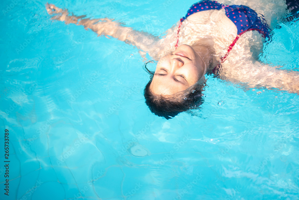 Asian woman in a blue bikini  swims in the pool , summer vacation