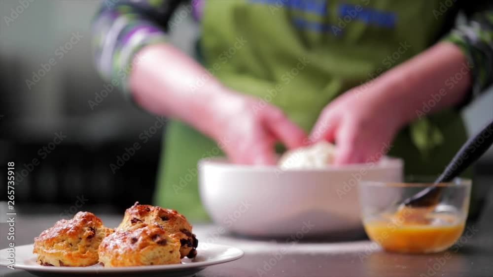 Scones coming into focus with baker in a kitchen in background Scones coming into focus with baker in a kitchen in background
