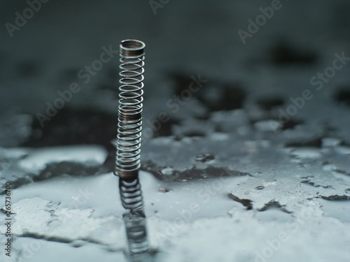 metal spring isolated on black background with reflection. Macro photography