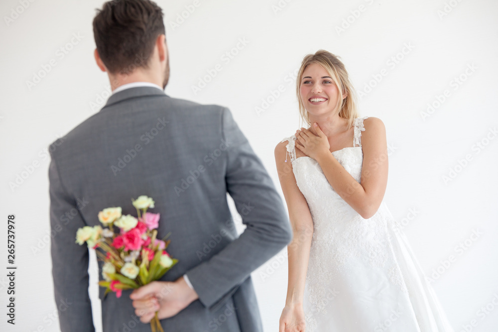 Man brings flowers to woman and hiding them behind back, Young woman looking at man with flower bouquet behind the back. Man brings flowers to woman and hiding them behind back, Young woman looking at man with flower bouquet behind the back.