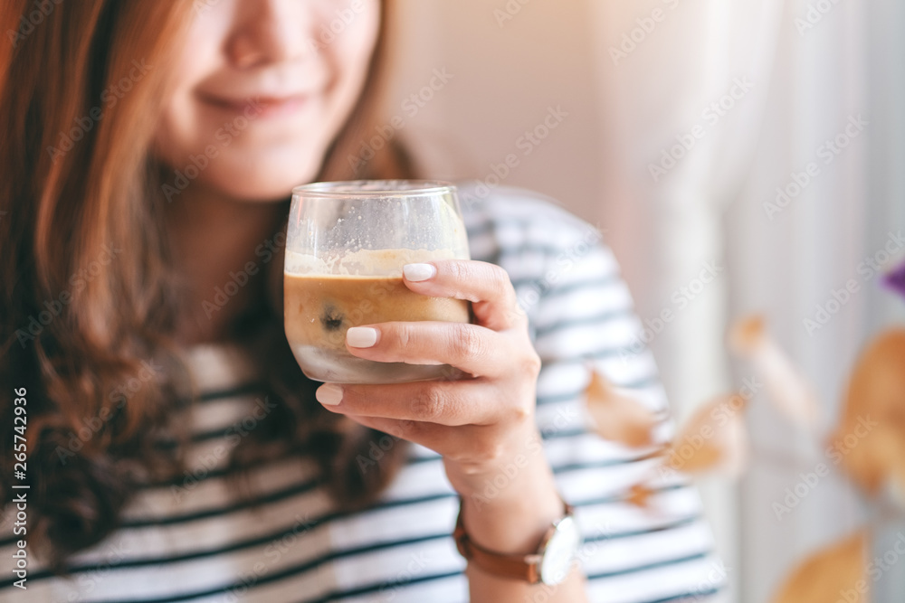 Closeup image of a beautiful woman holding a glass of iced coffee to drink in cafe Closeup image of a beautiful woman holding a glass of iced coffee to drink in cafe