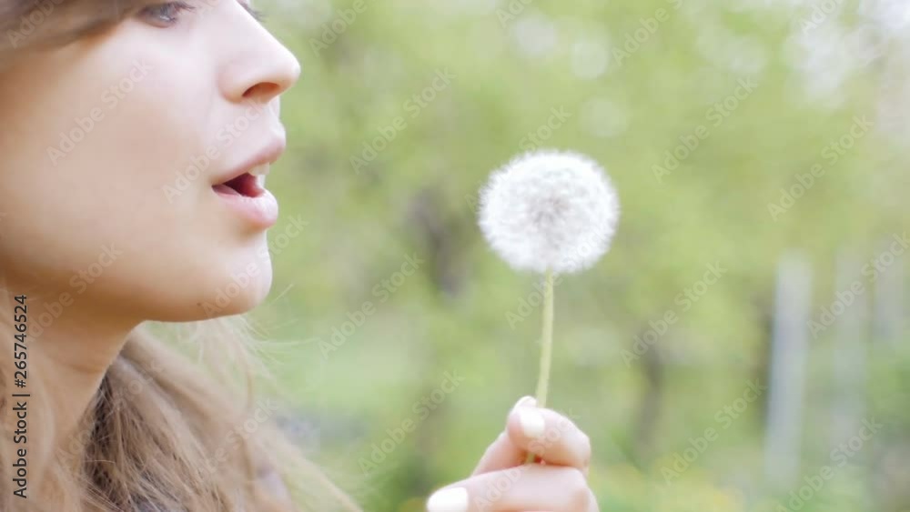 young beautiful woman blowing dandelion in the garden, rest and walk in spring, lovely girl on nature