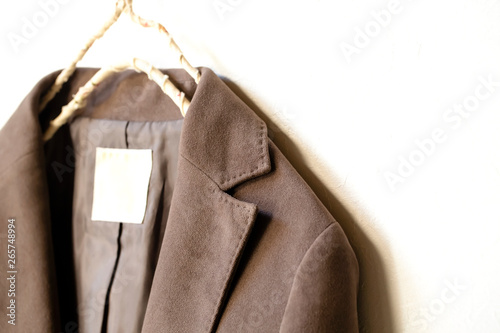 白バックとハンガーにかけた茶色のジャケットの肩や襟のクローズアップ