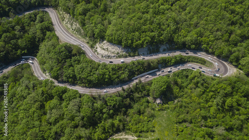 Winding road from the high mountain pass in South Russia. Great road trip trough the dense woods. Aerial view.