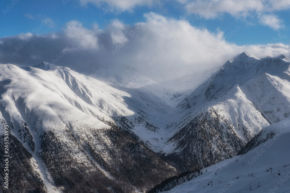 Obraz premium The sun, clouds and fog in Alpine Ski Resort And Ski Slopes in Winter, Livigno, Italy