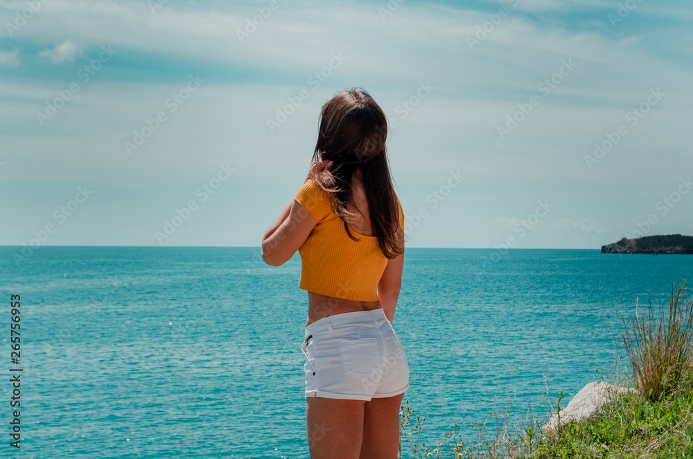 sporty young beautiful woman with a phone in her hand posing on a background of mountains and the sea sporty young beautiful woman with a phone in her hand posing on a background of mountains and the sea